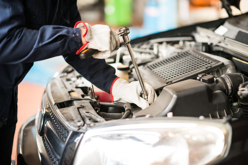 un homme travaillant sur un moteur de voiture dans un garage