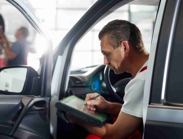 un homme assis dans une voiture écrivant sur un bloc-notes