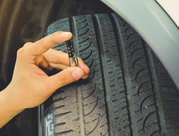 une personne tenant un pneu de voiture avec un tournevis