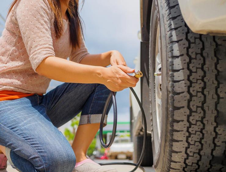 une femme vérifie la pression d'un pneu