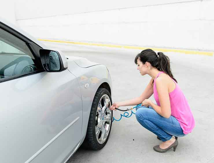 Une femme gonfle un pneu de voiture 