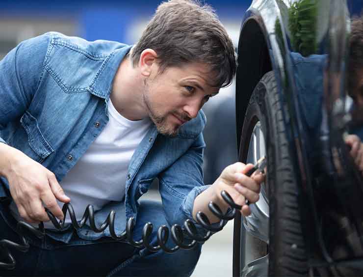 Un homme gonfle un pneu de voiture 